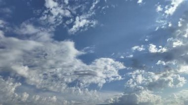 Mavi gökyüzünde huzur içinde süzülen beyaz bulutların barışçıl zamanlaması