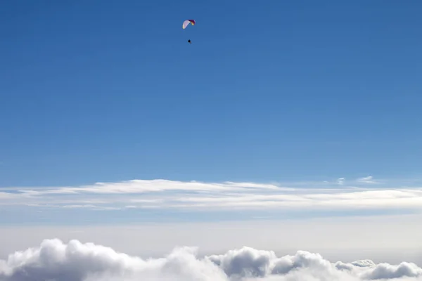 太陽の光の雲とパラグライダーのシルエットを持つ青い空冬の日 — ストック写真