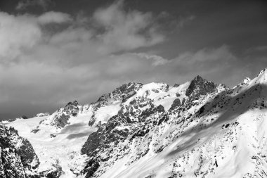 Güneşli bir günde, buzlu ve bulutlu gökyüzü ile karlı dağları seyret. Kışın Kafkas Dağları. Gürcistan 'ın Svaneti bölgesi. Siyah ve beyaz tonlu manzara.