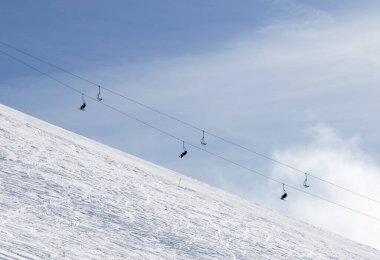 Kayak ve snowboard izleri olan karlı bir pistte kayak pisti ve bulutlu bir sandalyede kaldırma. Kışın Kafkasya Dağları, Gürcistan, Gudauri bölgesi. 