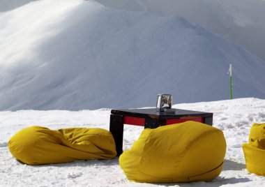 Sarı fasülye koltukları ve kayak merkezindeki açık kafede eski masa ve kış güneşinde serbest dolaşmak için kar yamacı..