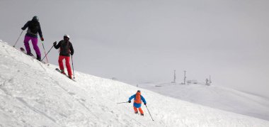 Kar yamacındaki kayakçıların panoramik manzarası ve kar fırtınasından önce bulutlu gökyüzü. Kışın Kafkasya Dağları, Gürcistan, Gudauri bölgesi.
