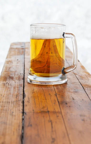 スキー場の冬の屋外カフェで木のベンチに新鮮な冷たいビールとガラスマグカップ — ストック写真