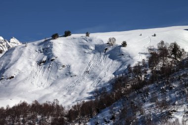 Kayaklardan, kar kayaklarından ve güneşli kış akşamlarında çığ altında kalan karlı bir yokuş. Kafkas Dağları, Gürcistan 'ın Svaneti bölgesi.