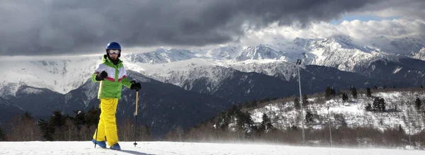 Junger Skifahrer Mit Skistöcken Sonnigen Schneebedeckten Bergen Und Bewölktem Grauen — Stockfoto
