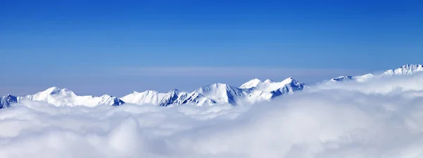 Panoramiczny Widok Wysokie Góry Śnieżne Chmurach Błękitne Niebo Słoneczny Zimowy — Zdjęcie stockowe