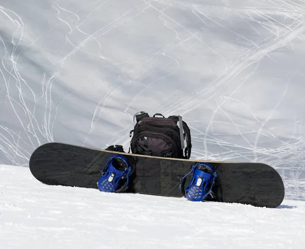 高い冬の山では雪の上に雪と黒のバックパック 背景にはスキーやスノーボードの痕跡がある雪のオフゲレンデ ストック画像