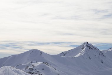 Karlı yamaçlarda yolu olan yüksek kış dağları ve sabahları güneşli bulutlu gökyüzü. İtalyan Alpleri. Levigno, Lombardiya bölgesi, İtalya, Avrupa.