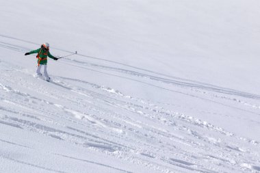 Snowboarder downhill on snowy off piste slope with newly-fallen snow at high winter mountains