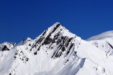 Snowy mountains peak and blue clear sky at sunny winter day. Caucasus Mountains. Georgia, region Gudauri. 