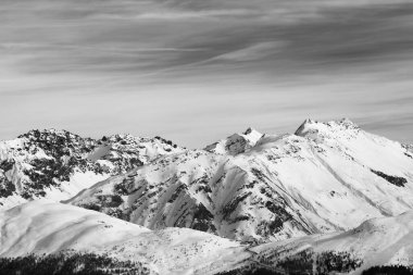 Snowy slope in high winter mountains and beautiful sunlit cloudy sky. Italian Alps. Livigno, region of Lombardy, Italy, Europe. Black and white toned landscape.