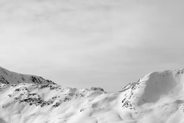 High winter mountains with snowy slopes and sunlit cloudy sky. Italian Alps. Livigno, region of Lombardy, Italy, Europe. Black and white toned landscape