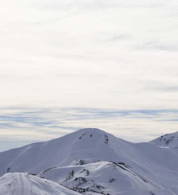 Karlı yamaçlarda yolu olan yüksek kış dağları ve sabahları güneşli bulutlu gökyüzü. İtalyan Alpleri. Levigno, Lombardiya bölgesi, İtalya, Avrupa.