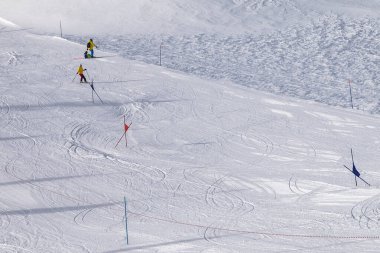 Trace for ski slalom with gates marked by flags, prepared by snowcat and off piste slope in snowy high mountains at sunny winter day. Italian Alps. Livigno, region of Lombardy, Italy, Europe.