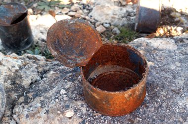 Open old rusty tin cans covered with ash on rock. Concept of environmental pollution, ecological problems.