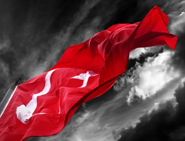 Flag of Turkey waving against black and white dark storm sky. Close-up view.