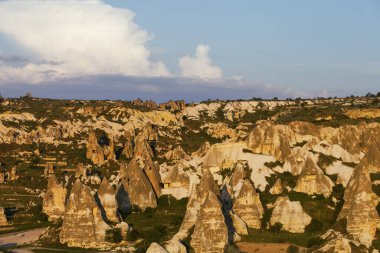 View on evening sunlit Cappadocia valley with cave houses in rocks in spring. Turkey, Goreme.