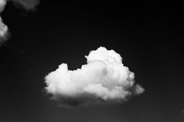 White clouds on black sky at sun summer day. Natural background. Black and white toned image.