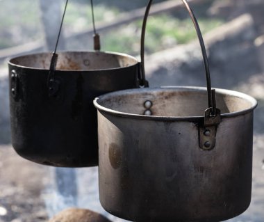 Güneşli bir günde kamp ateşinde iki eski kazanda yemek pişirmek. Görüntüyü kapat.