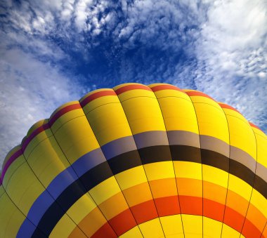 Bulutlu mavi gökyüzünde çok renkli sıcak hava balonu 