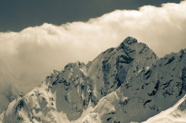 High winter snowy mountains in clouds. Caucasus Mountains, region Dombay. Retro color toned landscape.