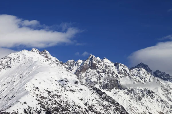 High snowy winter mountains and blue sky with clouds at sun day. Caucasus Mountains. Svaneti region of Georgia.