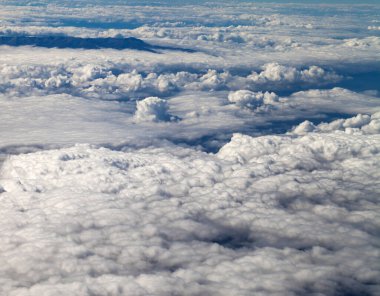 Airplane view on clouds and mountains in sun summer day