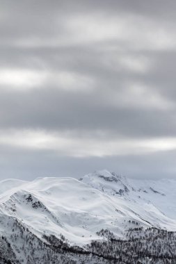 Snowy mountains and gray cloudy sky at winter. Caucasus Mountains. Svaneti region of Georgia.