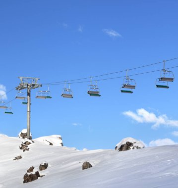 Sunlight chair-lift and blue sky with clouds at ski resort on sunny day. Caucasus Mountains in winter, Shahdagh, Azerbaijan.