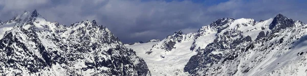 Panorama of snowy mountains with glacier in storm clouds at winter. Caucasus Mountains. Svaneti region of Georgia