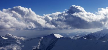 Karlı güneşli dağların panoramik manzarası ve kış akşamları bulutlu mavi gökyüzü. Kafkasya Dağları, Gürcistan, Gudauri bölgesi