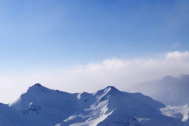 Siste yüksek karlı dağlar ve kış akşamı güneşli bulutlu gökyüzü. Kafkasya Dağları, Gürcistan, Gudauri bölgesi.