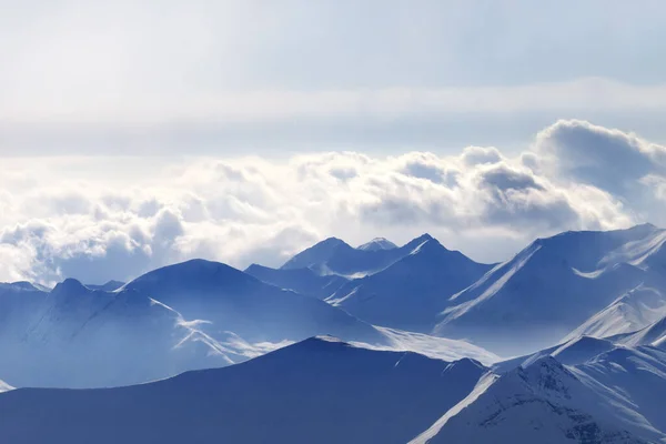 Silhouette Von Hohen Schneebedeckten Bergen Nebel Und Sonnenbeschienenen Bewölkten Himmel — Stockfoto