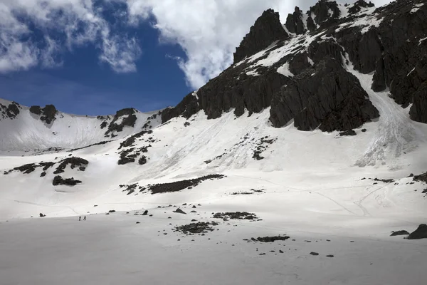 阳光普照的高山 雪冠雪崩的轨道 雪地的高原和两个小轮廓的徒步旅行者在晚上 土耳其 卡其卡山脉 庞蒂克山脉的最高峰 — 图库照片
