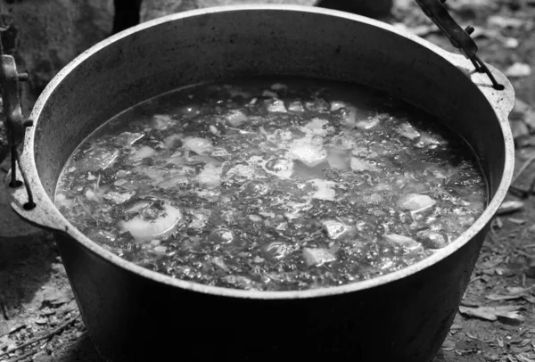 キャンプファイヤーの上で 新鮮な釜で熱々のスープを調理 屋外キャンプ料理 黒と白のトーン画像 ストックフォト