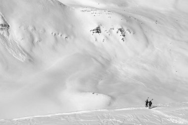 Omzunda kayak izleri, kayak, snowboard ve çığ izleri olan iki kayakçı. Gudauri bölgesinde, Gürcistan 'da, Kafkasya Dağları' nın güneşli kış gününde. Siyah ve beyaz tonlu manzara.