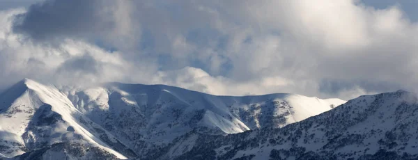 Panoramautsikt Över Snöiga Berg Med Skog Och Solljus Molnig Himmel — Stockfoto