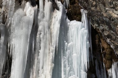 Kış güneşinde buzlu dağ şelalesi