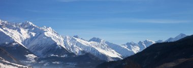 Panoramic view on snowy mountains and beautiful blue sky in nice sunny morning. Caucasus Mountains at winter. Svaneti region of Georgia.
