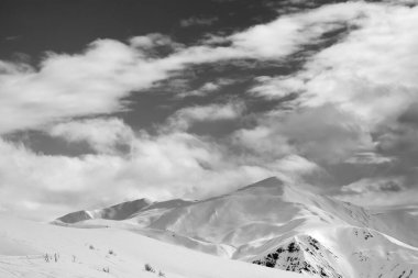 Black and white snowy ski slope and sky with clouds in winter evening. Tetnuldi, Caucasus Mountains, Svaneti region of Georgia.