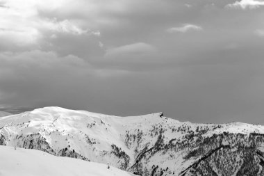 Güneş ışığı karlı dağlar ve kış akşamları bulutlu gri gökyüzü. Kafkasya Dağları, Gürcistan 'ın Svaneti bölgesi. Siyah ve beyaz tonlu manzara.