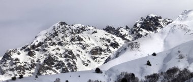 Karlı güneş ışığı dağı ve gri kış akşamında bulutlu gökyüzü. Kafkas Dağları. Gürcistan 'ın Svaneti bölgesi. Panoramik görünüm.