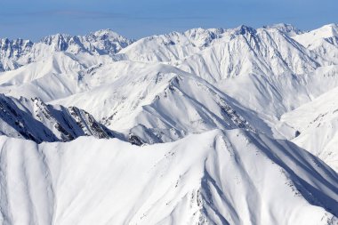 Yüksek karlı dağlar ve soğuk kış gününde bulutlu mavi gökyüzü. Kafkasya Dağları, Gürcistan bölgesi Gudauri.