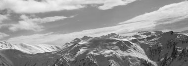 Karlı dağların panoramik manzarası ve kış akşamları bulutlu güneş ışığı gökyüzü. Kafkas Dağları. Gürcistan 'ın Svaneti bölgesi. Siyah ve beyaz tonlu manzara.