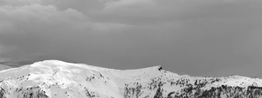 Güneşli karlı dağların panoramik manzarası ve kış akşamları bulutlu gri gökyüzü. Kafkasya Dağları, Gürcistan 'ın Svaneti bölgesi. Siyah ve beyaz tonlu manzara.