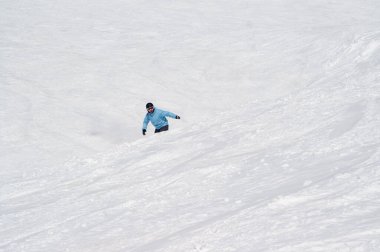Güneşli bir günde, yüksek kış dağlarında karlı kayak pistine atlamadan önce snowboardcu.