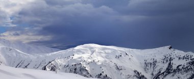 Karlı güneş ışığı yamacında panoramik manzara ve kış akşamları bulutlu gri gökyüzü. Kafkas Dağları, Gürcistan 'ın Svaneti bölgesi.