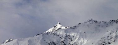Karlı, güneşli dağ zirvesinde panoramik manzara ve kış akşamları bulutlu gökyüzü. Kafkas Dağları, Gürcistan 'ın Svaneti bölgesi.