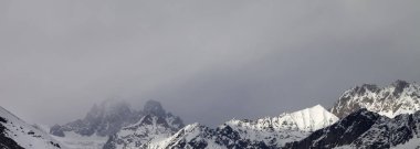 Yağmurdan önceki gri günde karlı güneş ışığı dağının sisli manzarası. Kışın Kafkas Dağları. Gürcistan 'ın Svaneti bölgesi