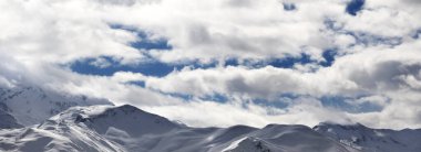 Karlı dağların panoramik manzarası ve kış akşamları güneş ışığı bulutlu gökyüzü. Kafkas Dağları. Gürcistan 'ın Svaneti bölgesi.